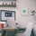 Medicine cabinet with green cross on white door, wall-mounted in office environment beside desk.