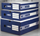 Three stacked blue A4 archive boxes with white labels on studio background.