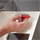 Hand inserting red rectangular accessory with holes into a white product.