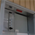 Open electrical consumer unit with circuit breakers and main switch, mounted on light wooden panelling.