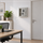 Grey wall-mounted safe with code lock, door ajar showing two shelves, in an office environment.